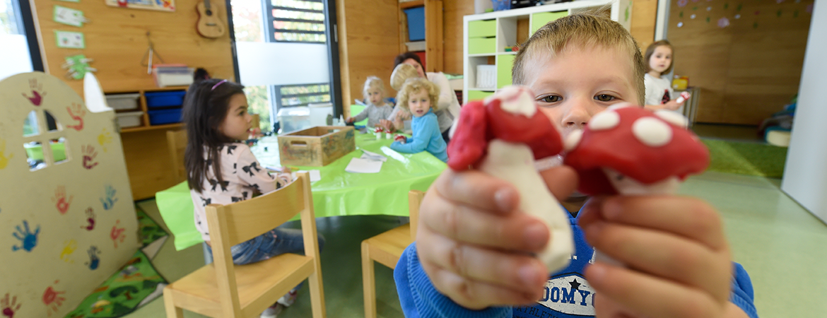 Kind präsentiert in der Kita gebastelte Pilze