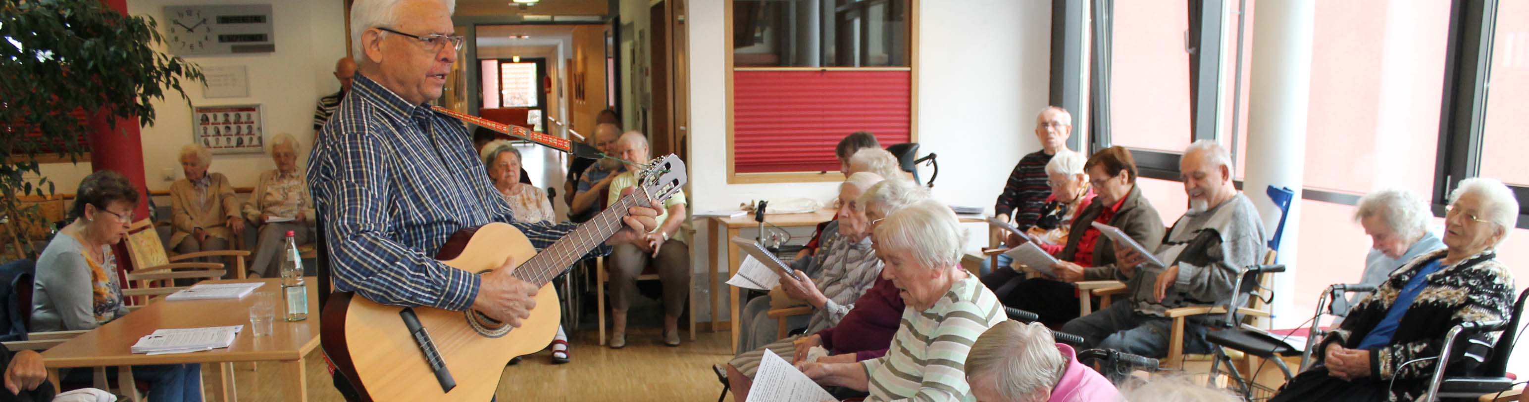 Ein Ehrenamtlicher spielt Gitarre für die Bewohner*innen