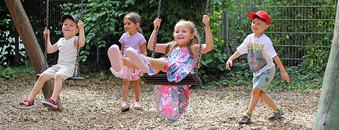 Kinder schaukeln im Garten der AWO-Kita "Wurzelkinder"