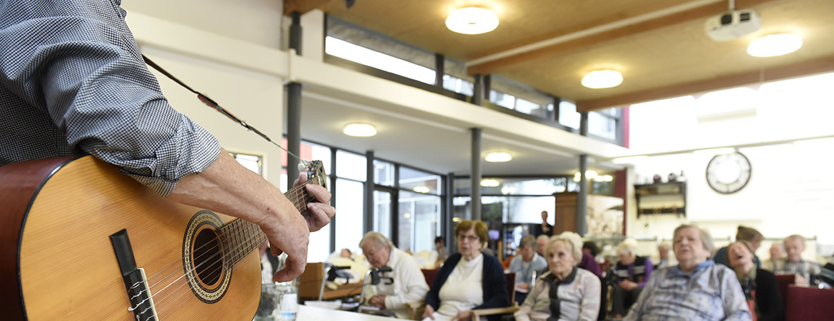 Ein Ehrenamtlicher spielt Gitarre für die Bewohner*innen